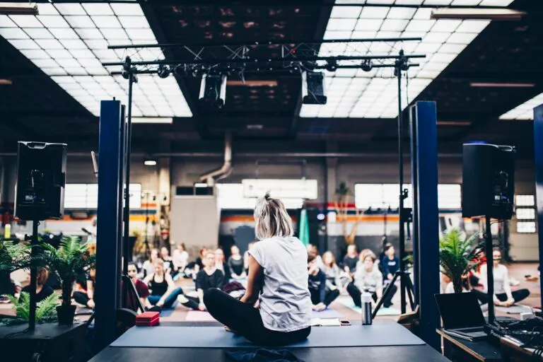 Fitness coach in a modern studio setting with a coaching platform interface visible on screen